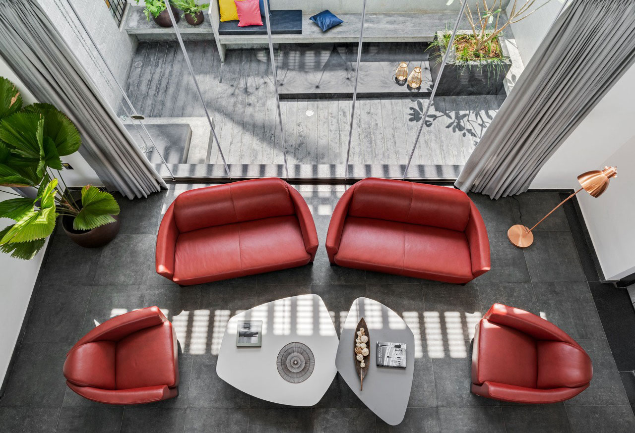 The cut out area viewed from the bridge on the first floor where the contrast of the furniture can be seen on the exposed concrete flooring and a green backdrop.