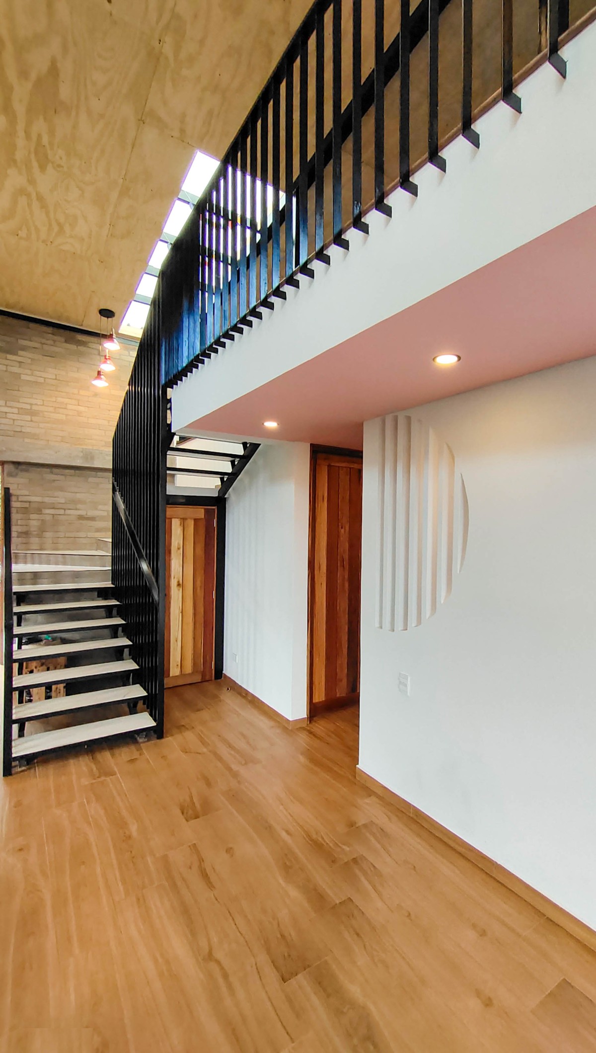 Mezzanine overlooking the living and open kitchen area, with a common railing detail for the stairs and the floor above