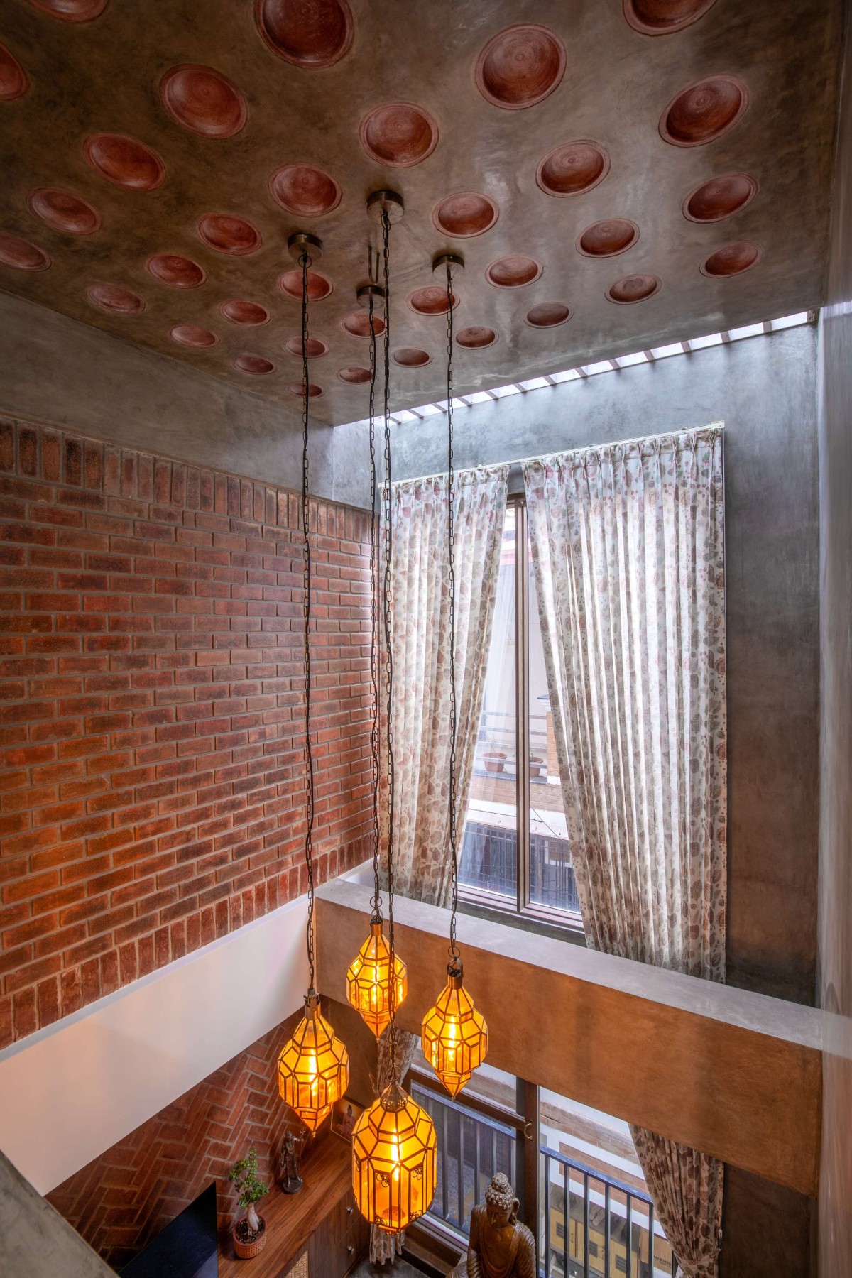 The filler slab ceiling, at double height, is accentuated with terracotta pots – Kuteeram by Brick and Compass