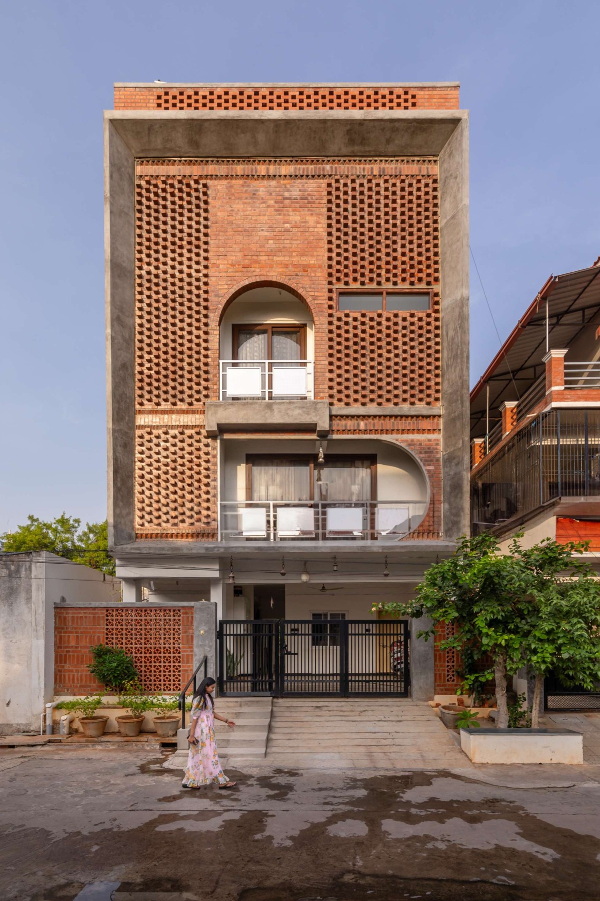 The dynamic wire-cut brick West façade with strategically placed arches – Kuteeram by Brick and Compass