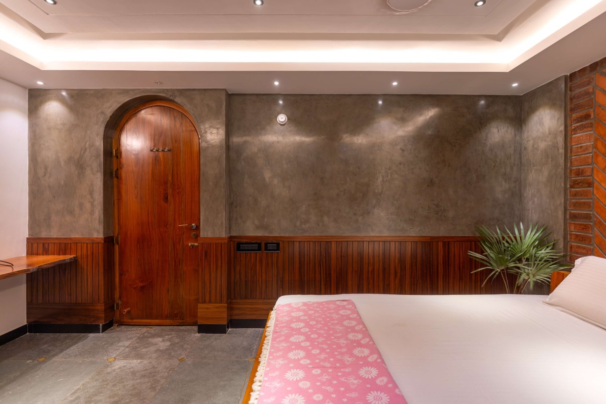 Master Bedroom finished with Grey Oxide in contrast to exposed wire-cut brick wall, wooden wainscoting add warmth to the entire space  - Kuteeram by Brick and Compass